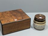 une petite boîte en bois avec un couvercle, posée à côté d'un petit bocal