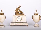 trois vases et une horloge posés sur une table