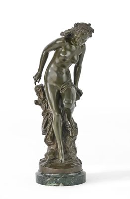 une statue antique en bronze représentant une femme tenant une fleur, posée sur un socle en marbre