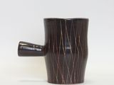 a black cup with a brown handle on a white surface