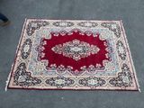 un tapis oriental posé à même le sol, devant lequel passe une personne