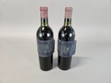 two bottles of red wine are sitting on a white surface
