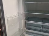 an open refrigerator with the door open and a hand reaching for the freezer
