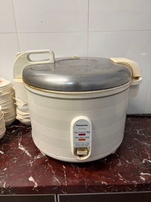 une mijoteuse posée sur un plan de travail, à côté d'une pile d'assiettes