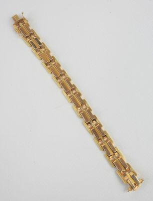 gros plan d'un bracelet en or sur une surface blanche