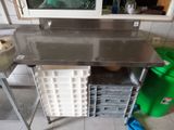 a stainless steel work table in a kitchen with a green trash can