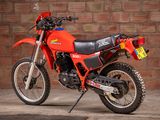 a red dirt bike parked in front of a brick wall