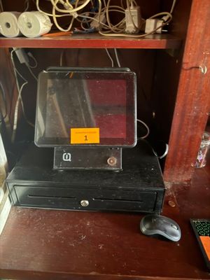 une caisse enregistreuse noire posée sur un bureau en bois