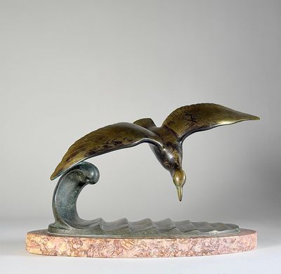 sculpture en bronze représentant un oiseau volant au-dessus d'une vague, posée sur un socle en marbre