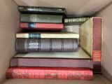 many books in a box that are stacked on top of each other