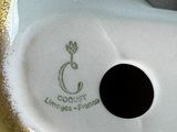 a close up of a white and gold vase on a table