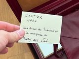 a hand holding a piece of paper with writing on it
