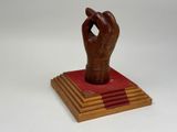 sculpture en bois représentant une main tenant un livre sur fond blanc