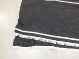 a black blanket with white fringes on the floor