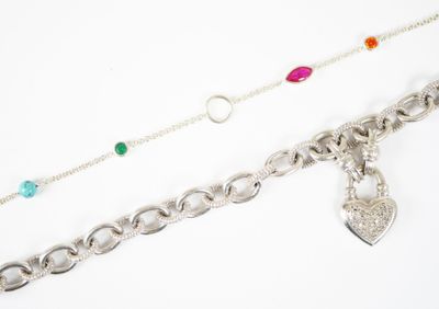 deux chaînes en argent ornées de pierres de différentes couleurs, posées sur un fond blanc