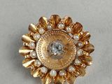 a close up of a gold brooch with pearls on it