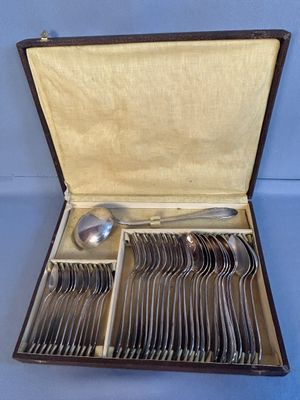 des couverts dans un coffret posé sur une table avec un fond bleu