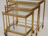 a pair of brass and glass nesting tables on casteors