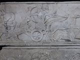 a stone relief of a man on a horse drawn carriage