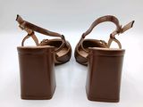 the woman ' s shoes are made of brown leather and are on a white surface