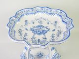 a blue and white plate on a stand on a table