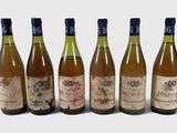 six bouteilles de vin sont alignées sur une surface blanche