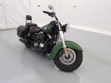une moto verte garée dans une pièce aux murs blancs