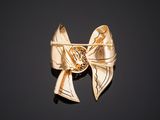 a gold bow brooch on a black surface