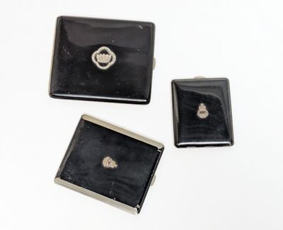 three small black and silver jewelry pieces sitting on top of a white surface