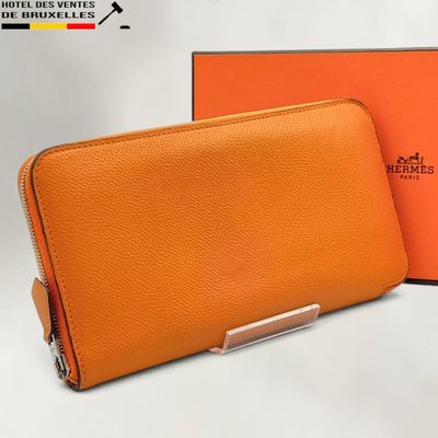 un portefeuille en cuir orange muni d'un fermoir en métal argenté et d'une boîte