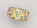 gros plan d'une bague en or avec des pierres multicolores