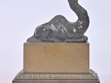 sculpture en bronze représentant un chameau posé sur un socle en bois, sur fond blanc