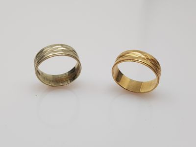 two gold rings on a white surface