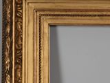 a close up of a gold framed mirror on a wall