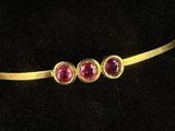 a close up of a gold belt with three ruby stones