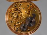 a close up of a gold pocket watch on a stand