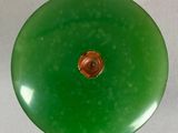 a green glass object with a brown button on it