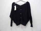 a black cardigan sweater hanging on a hanger on a white wall