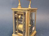 a gold clock with a glass case on a blue surface