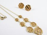 un gros plan d'un collier et de boucles d'oreilles en or posés sur une surface blanche