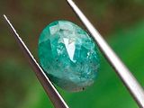 un gros plan d'un diamant vert tenu par une pince