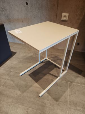 une petite table au plateau blanc posée sur un sol carrelé