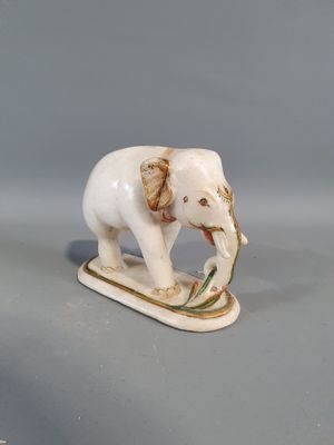 porcelain figurine of an elephant on a sled with a twig in its mouth