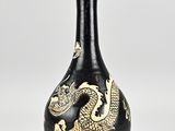 a black and gold vase with a dragon design on it