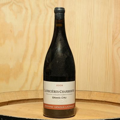 a bottle of wine sitting on top of a wooden barrel