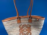 a close up of a straw bag with a leather handle on a blue background