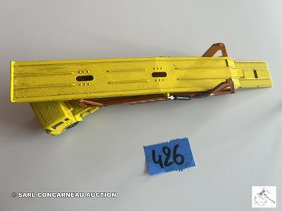 un pistolet jouet jaune auquel est attachée une étiquette bleue
