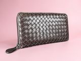 a brown leather wallet with a zipper closure on a pink background