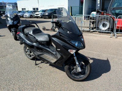 une moto noire garée sur un parking près d'une clôture