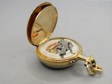 a small gold pocket watch with a key in it